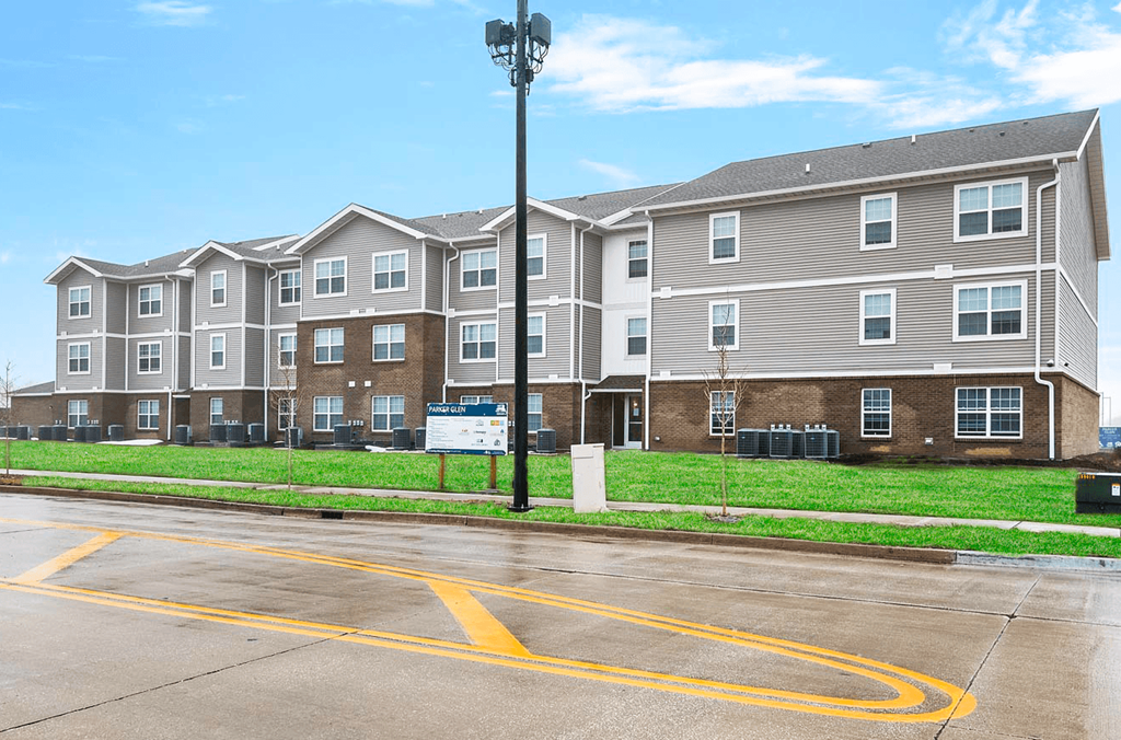 a large apartment building on the corner of a parking lot