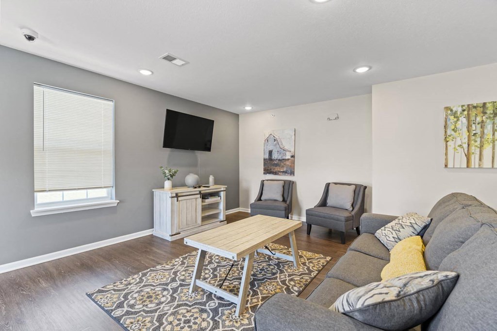 a living room with a couch and two chairs in front of a tv