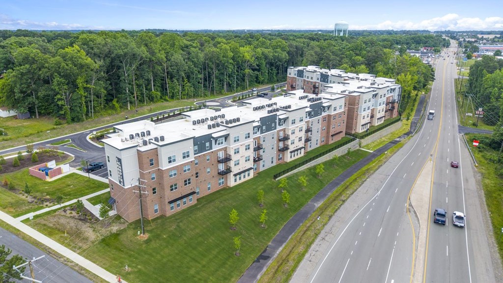 A multi-story apartment building is situated next to a busy road.
