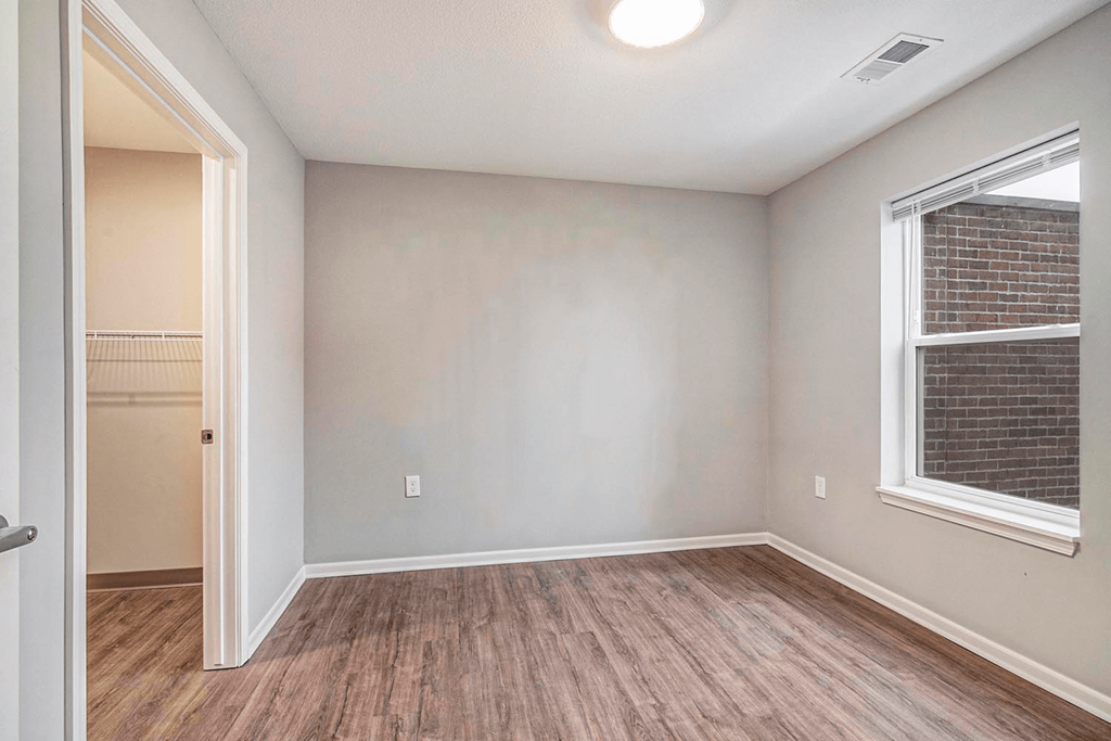 an empty living room with a large window and wooden floors