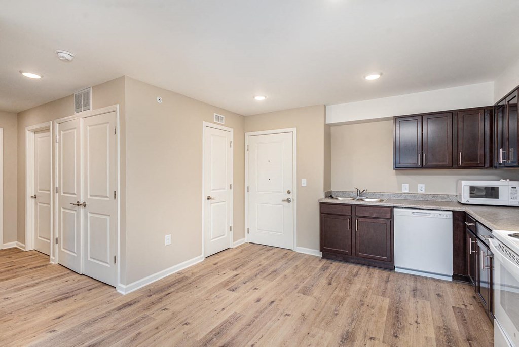 A kitchen with white appliances and wooden floors.