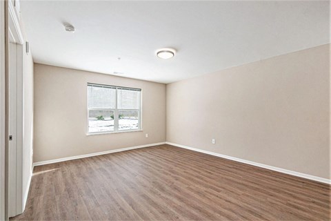 A room with a window and wooden flooring.