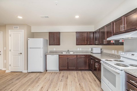 A kitchen with white appliances and wooden cabinets.