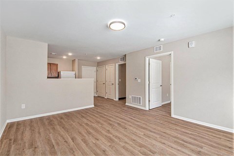 A room with a white ceiling and wooden flooring with a refrigerator and cupboard doors.