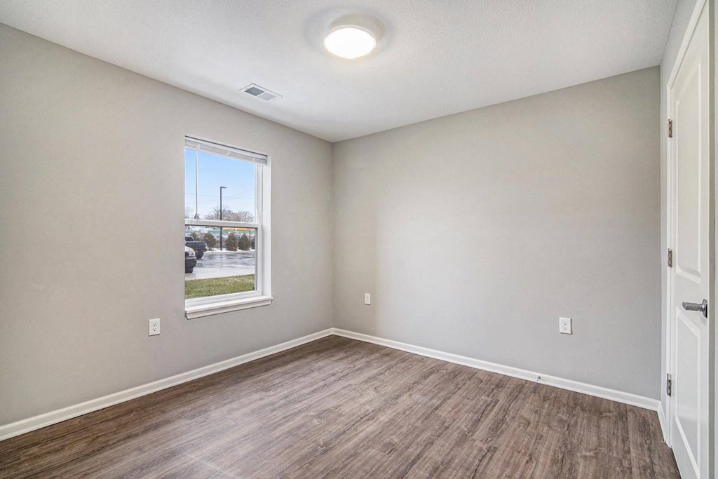 an empty room with wood flooring and a window