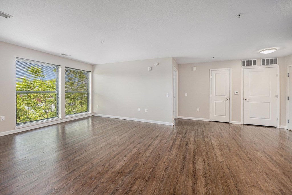 an empty living room with wood floors and a large window