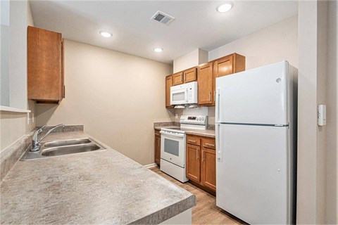 A kitchen with a white refrigerator, sink, and microwave.
