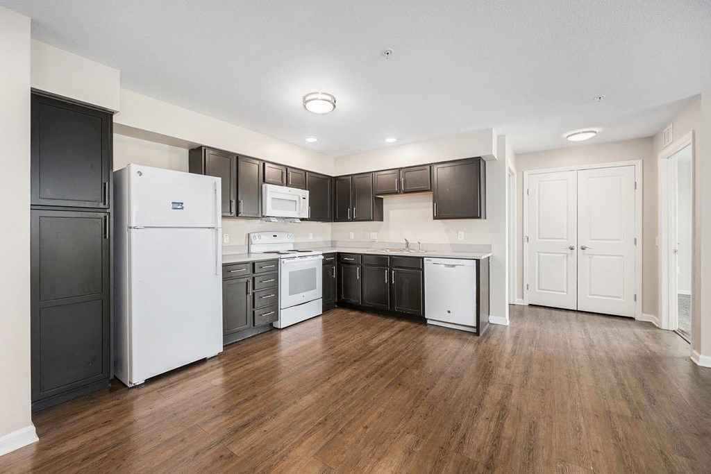 an empty kitchen with white appliances and black cabinets