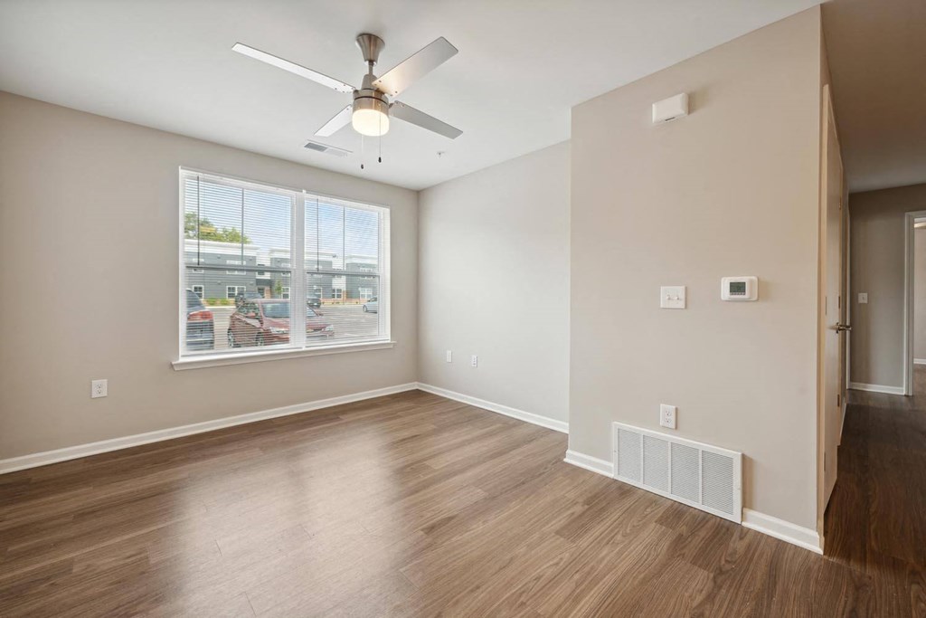an empty room with a large window and a ceiling fan