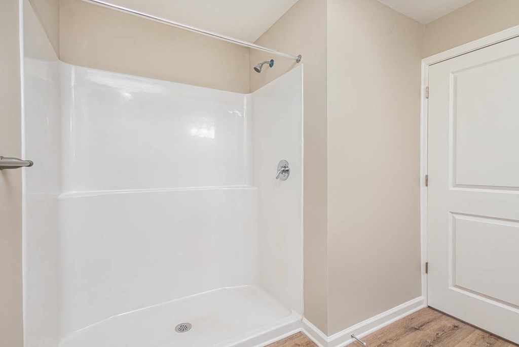A white shower stall with a door and a shower head.