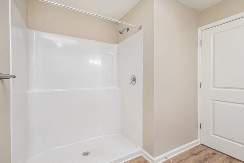 A white shower stall with a door and a shower head.