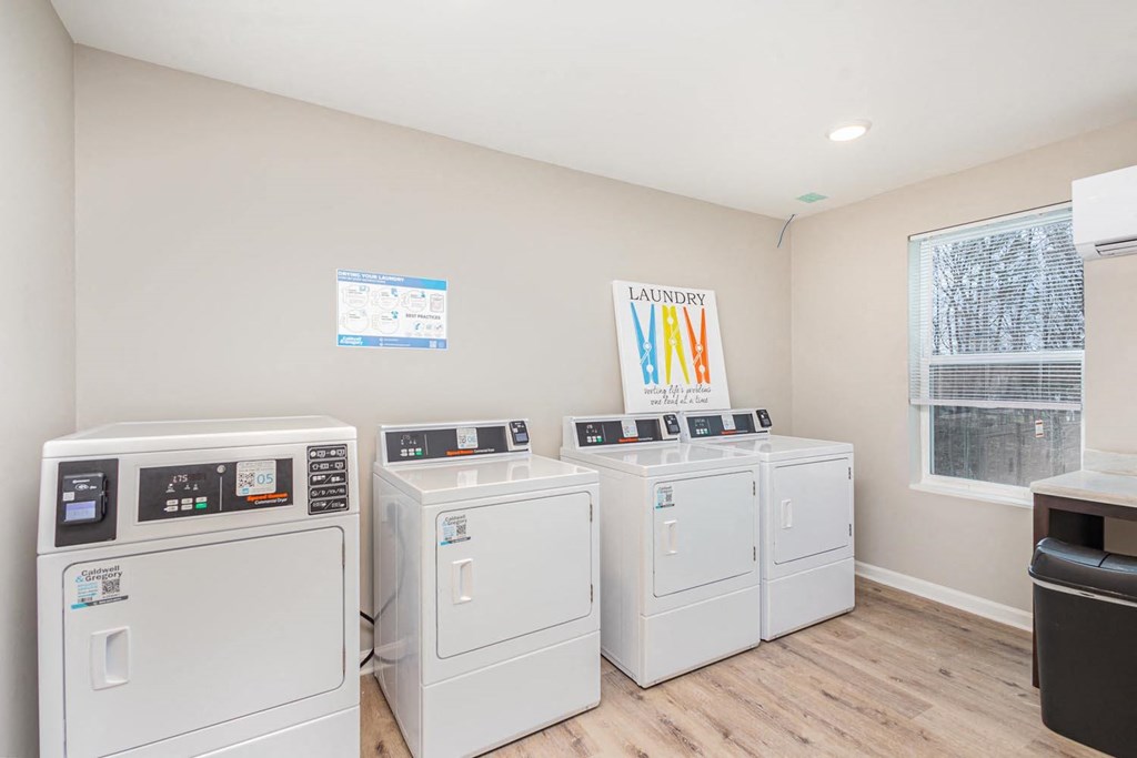 A laundry room with a row of washers and dryers.