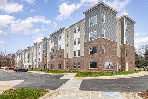A large apartment complex with a parking lot in front.