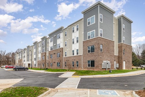 A large apartment complex with a parking lot in front.