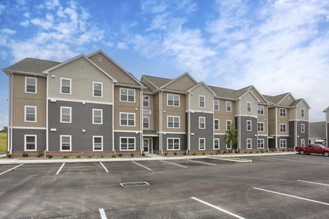 A row of apartment buildings with a red truck parked in the parking lot.