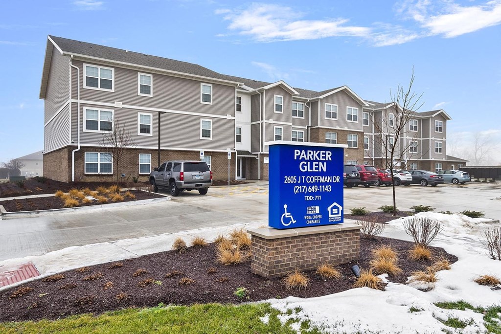 a parking sign in front of an apartment building in the snow