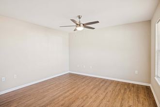 an empty living room with a ceiling fan and wood floors