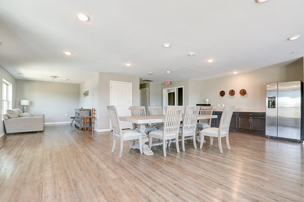 a large living room with a dining table and a refrigerator