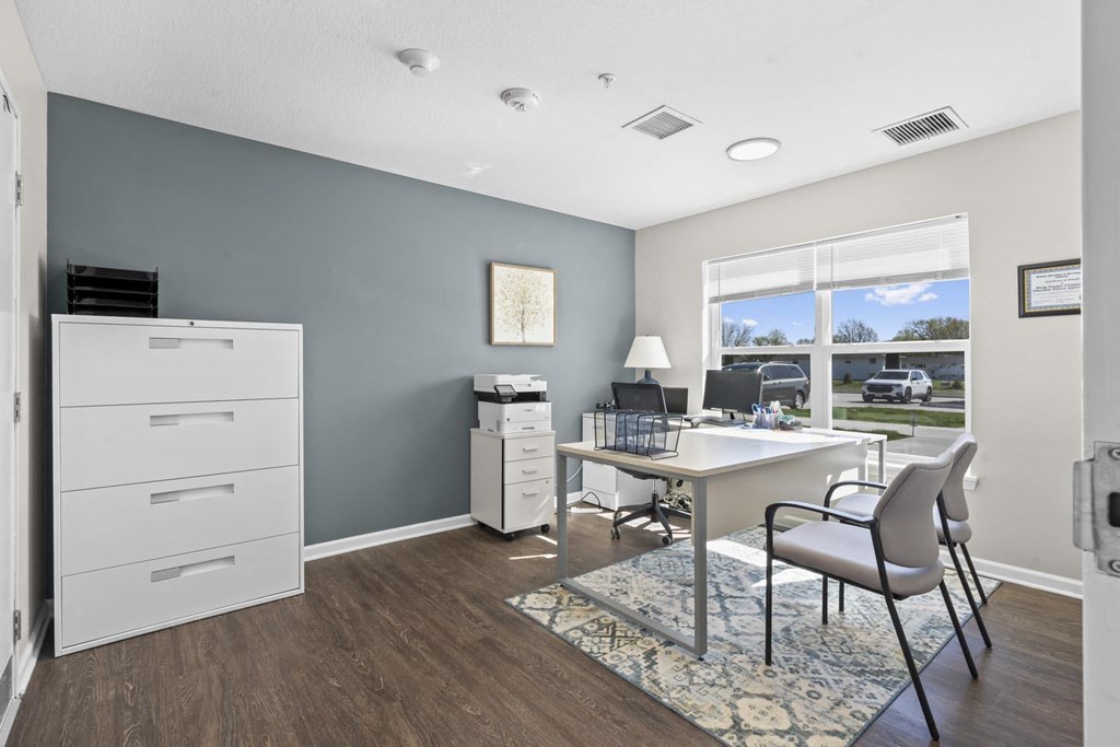 an office with a desk and chairs and a large window