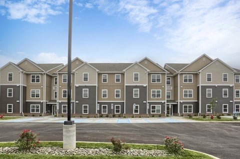 A large building with a grey and beige exterior is surrounded by a parking lot.