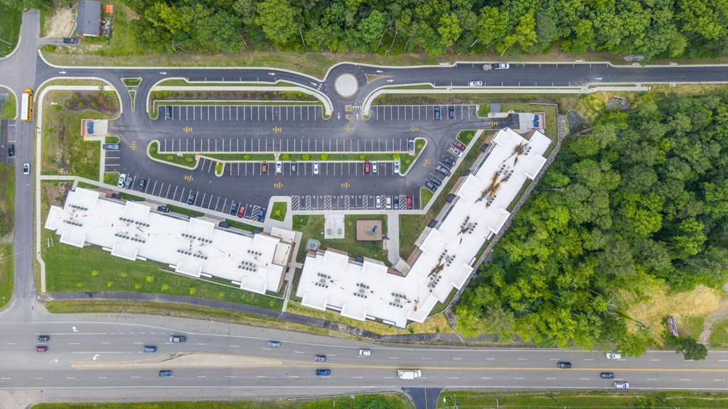 An aerial view of a roundabout with a parking lot and buildings.