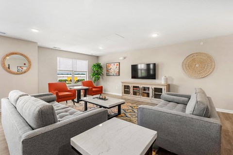 A living room with grey couches and a red chair.