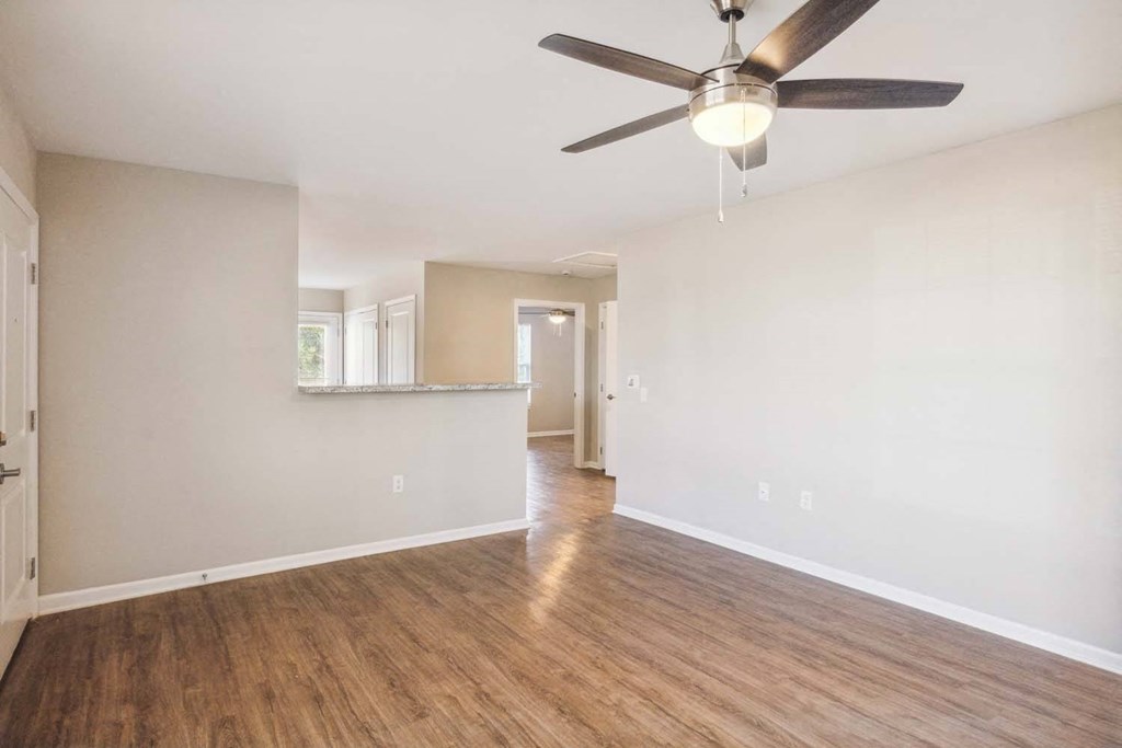 an empty living room and kitchen with a ceiling fan