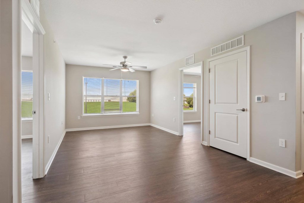 an empty living room with a ceiling fan and a window