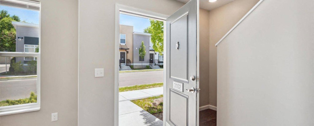 a white door opens to a sidewalk with houses in the background