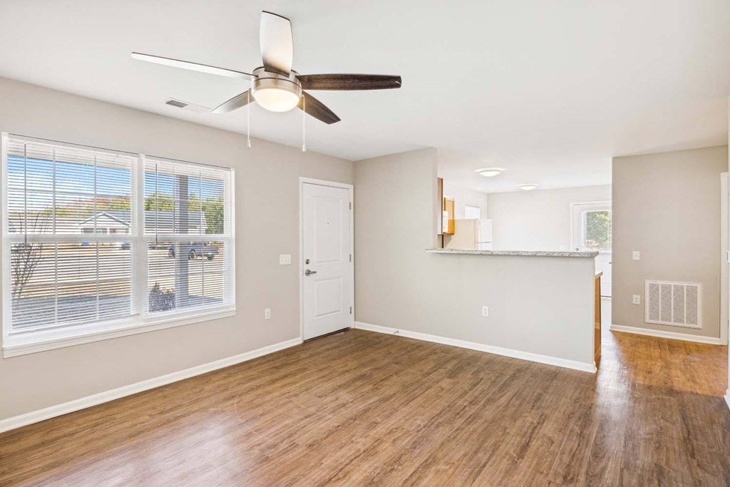 an empty living room with a ceiling fan and a window