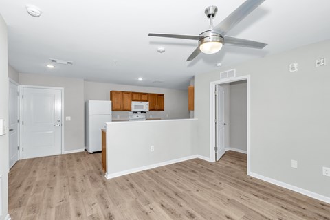 A room with a ceiling fan and a kitchenette.