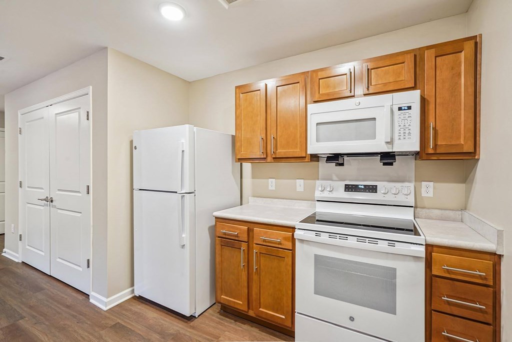 A kitchen with white appliances and wooden cabinets.