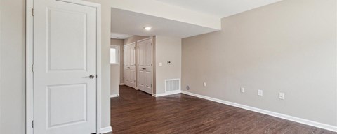 a living room with a white door and a hallway with a closet