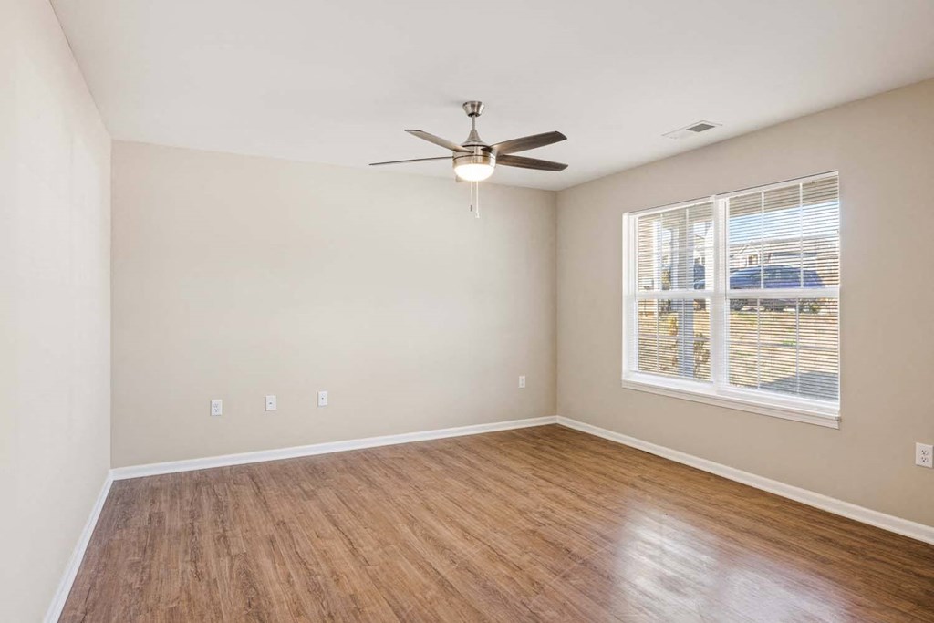 an empty living room with a ceiling fan and a window