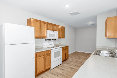 A kitchen with white appliances and wooden cabinets.