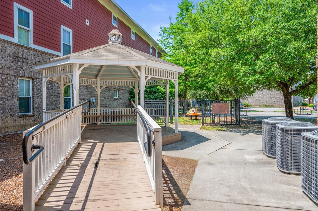 a covered walkway with a gazebo and a building with trees