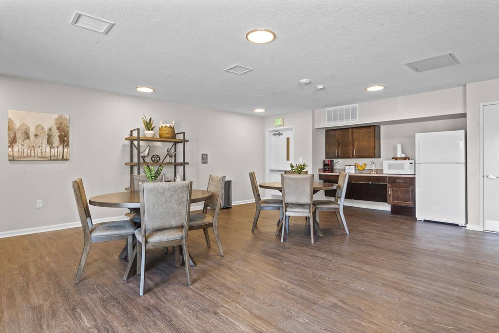 a dining area with a table and chairs and a kitchen in the background