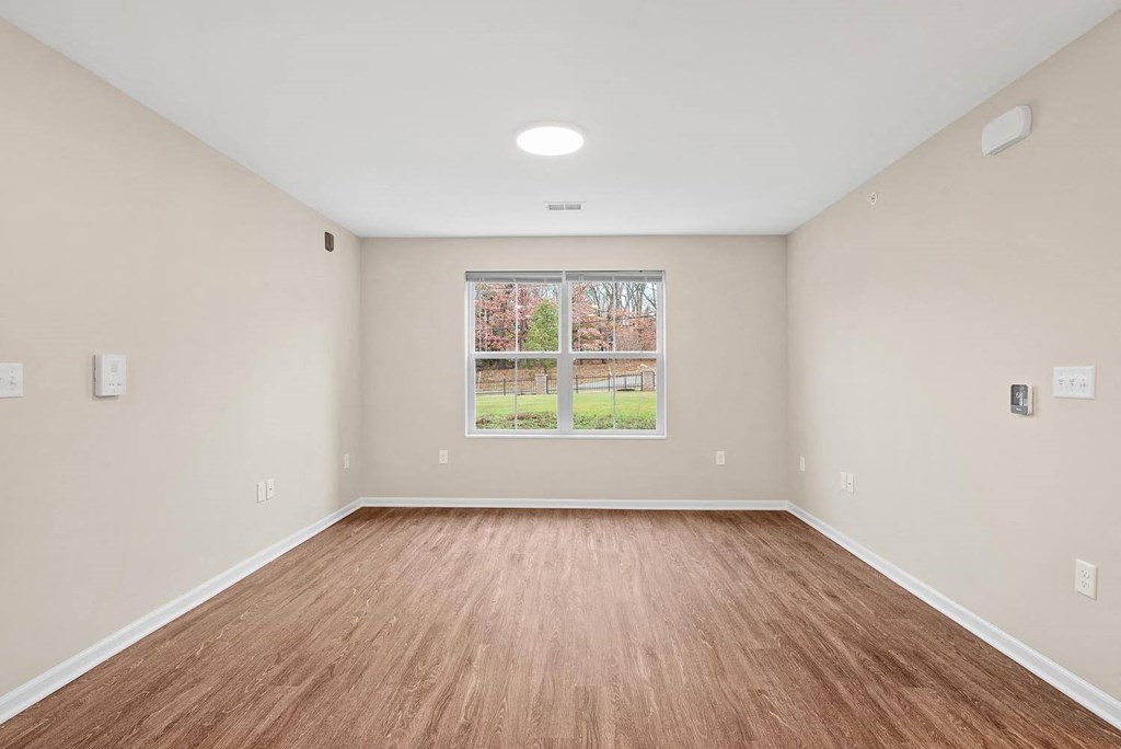 A room with wooden flooring and a window showing an outdoor view.