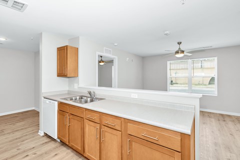A kitchen with white countertops and wooden cabinets.