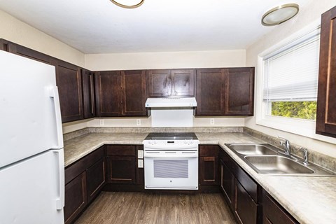 A kitchen with a white refrigerator and brown cabinets.