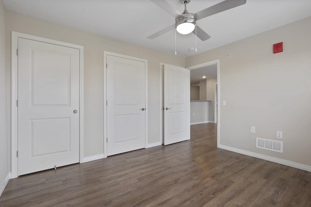 an empty living room with white doors and a ceiling fan