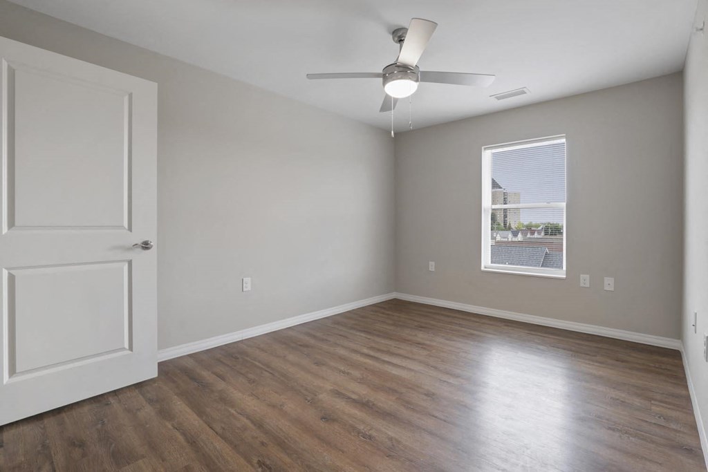an empty living room with wood floors and a ceiling fan