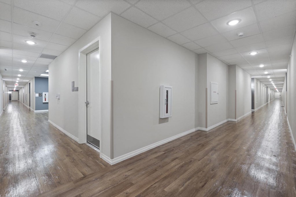 the corridor of a building with white walls and wood floors