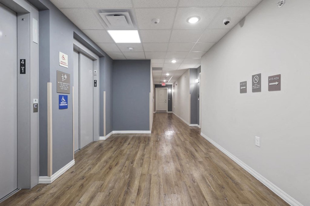 a long hallway with wood floors and grey walls and gray doors
