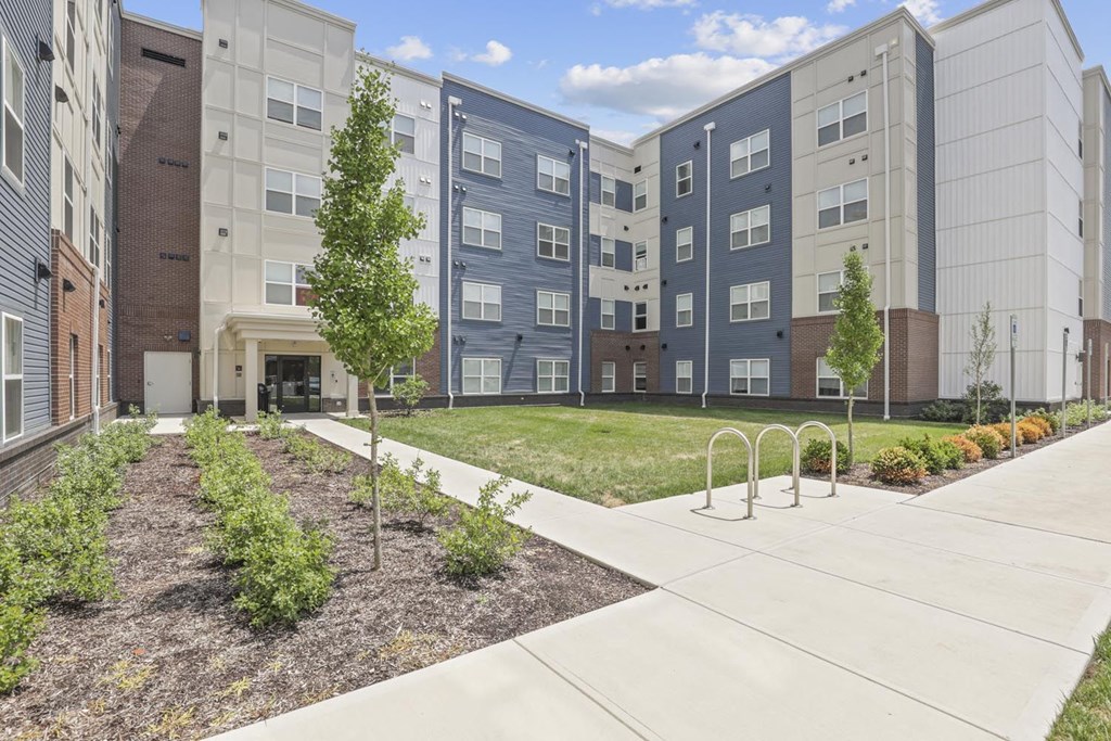 an exterior view of an apartment building with a sidewalk and grass