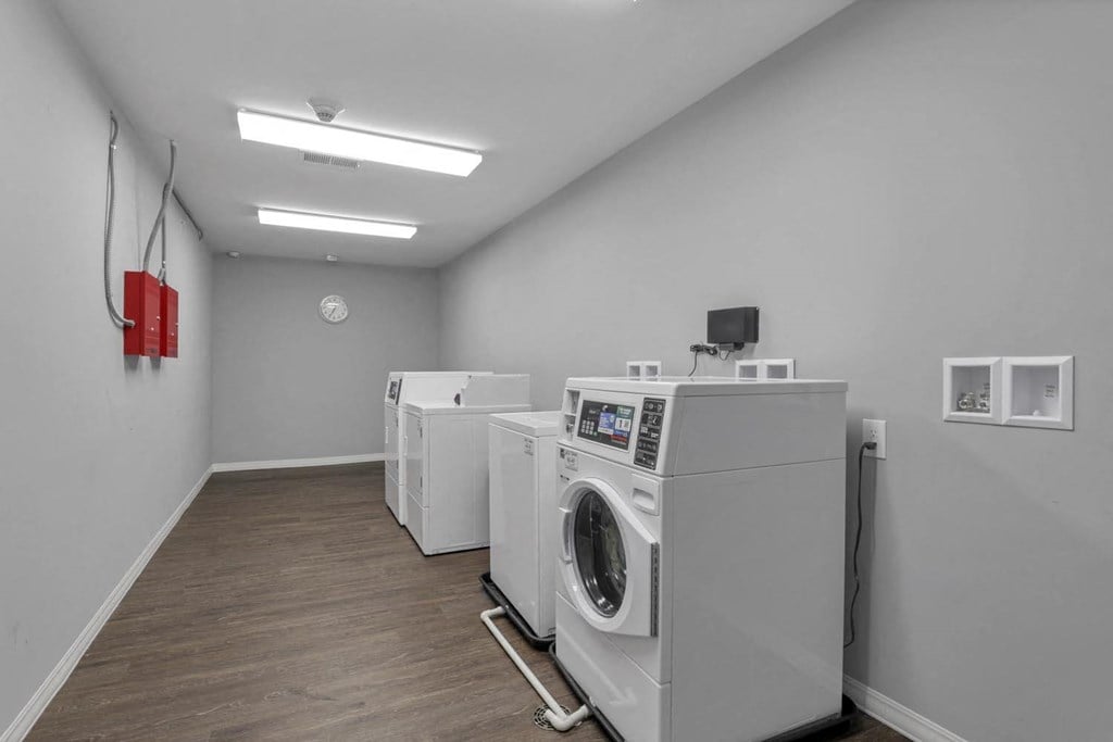 washing machines and dryers in a room with a wood floor