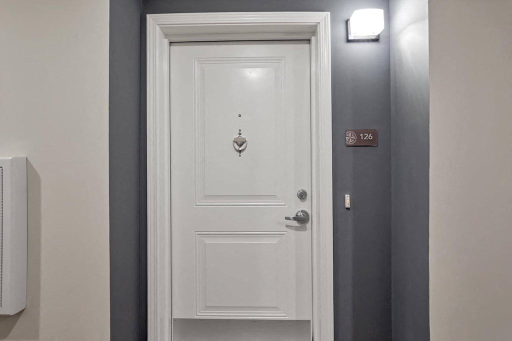 a white door with a silver door knob and a gray wall