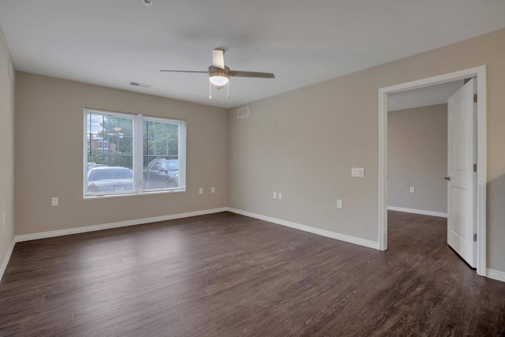 an empty living room with wood floors and a ceiling fan