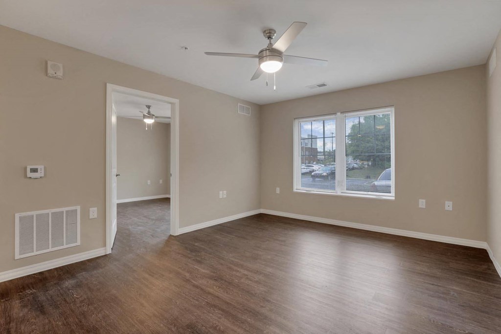 an empty living room with a ceiling fan and a window