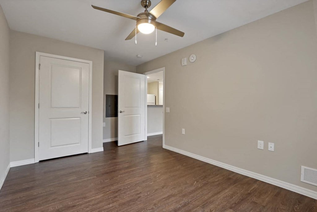 a living room with a ceiling fan and a door to a kitchen